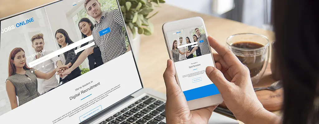 Mobile-first design on a phone with a laptop in the background for reference