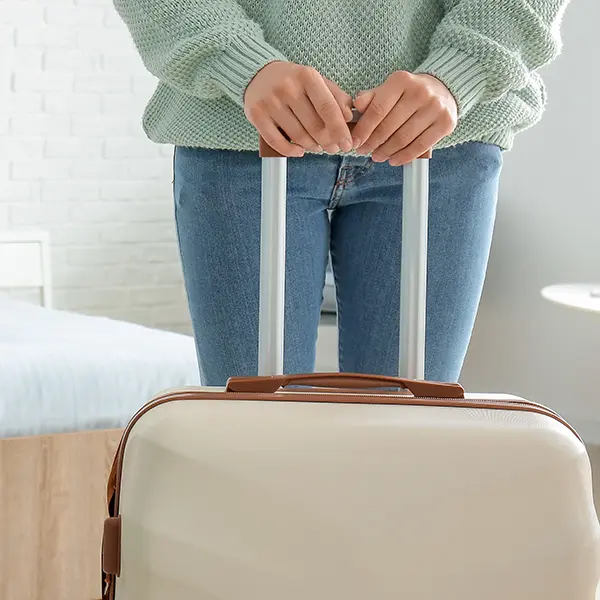 Female hotel guest arriving in room with rolling suitcase