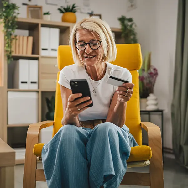 Senior woman making an ecommerce purchase from her phone at home