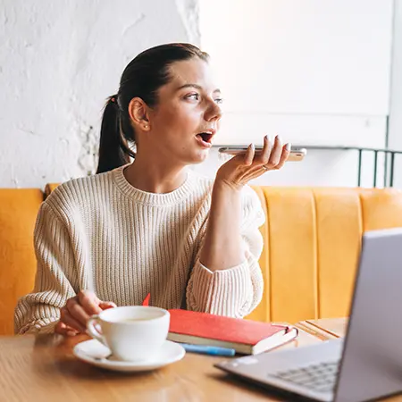 Female using voice activated search on her phone while drinking coffee